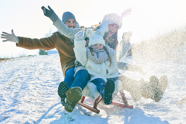 Familie fährt mit Schlitten durch die Schneelandschaft